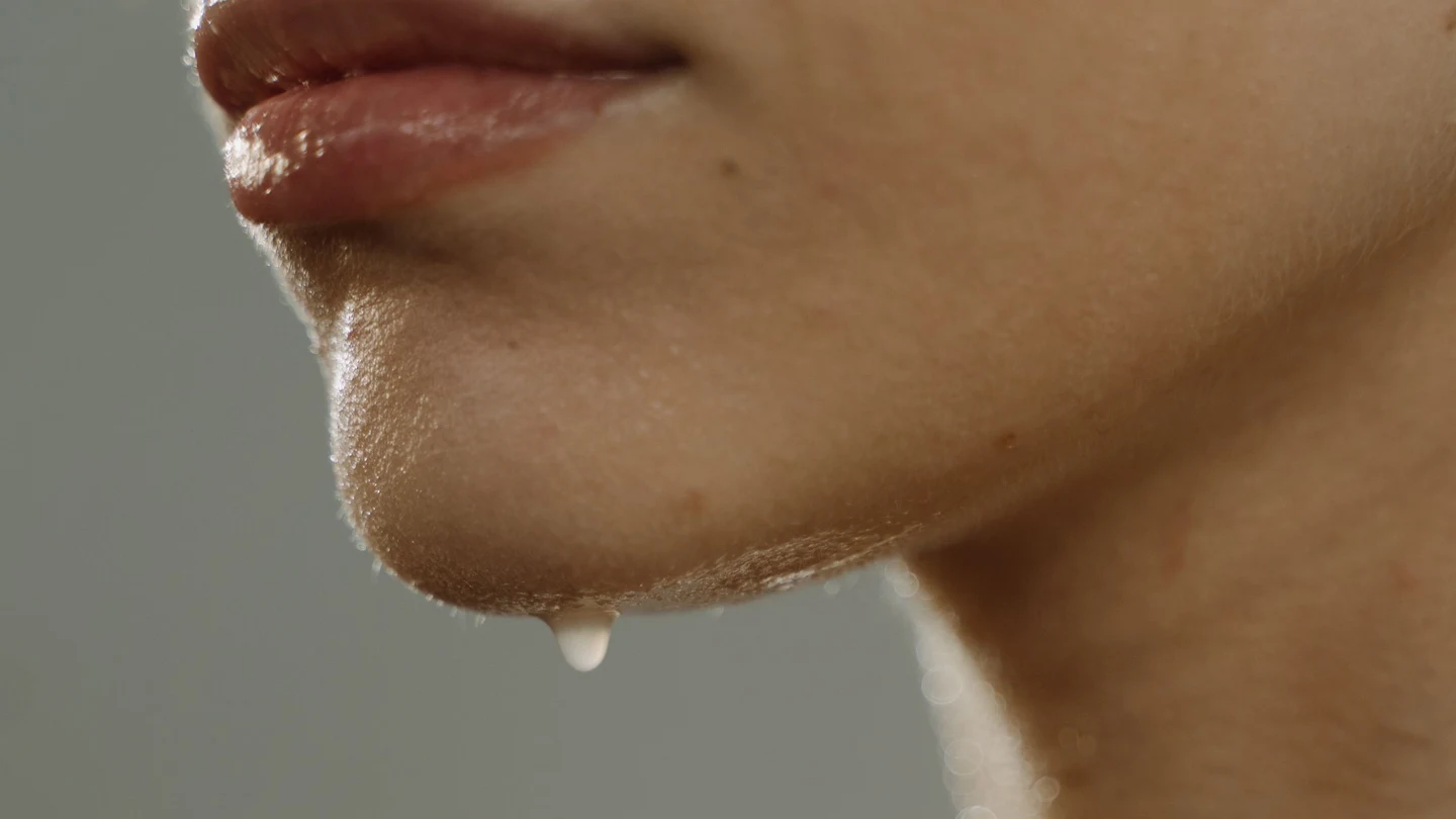 A dewy, water-glow (물광) finish catching the light — the sheen that reads as "glass" is as much about hydration, a luminous base, and soft lighting as it is about skincare