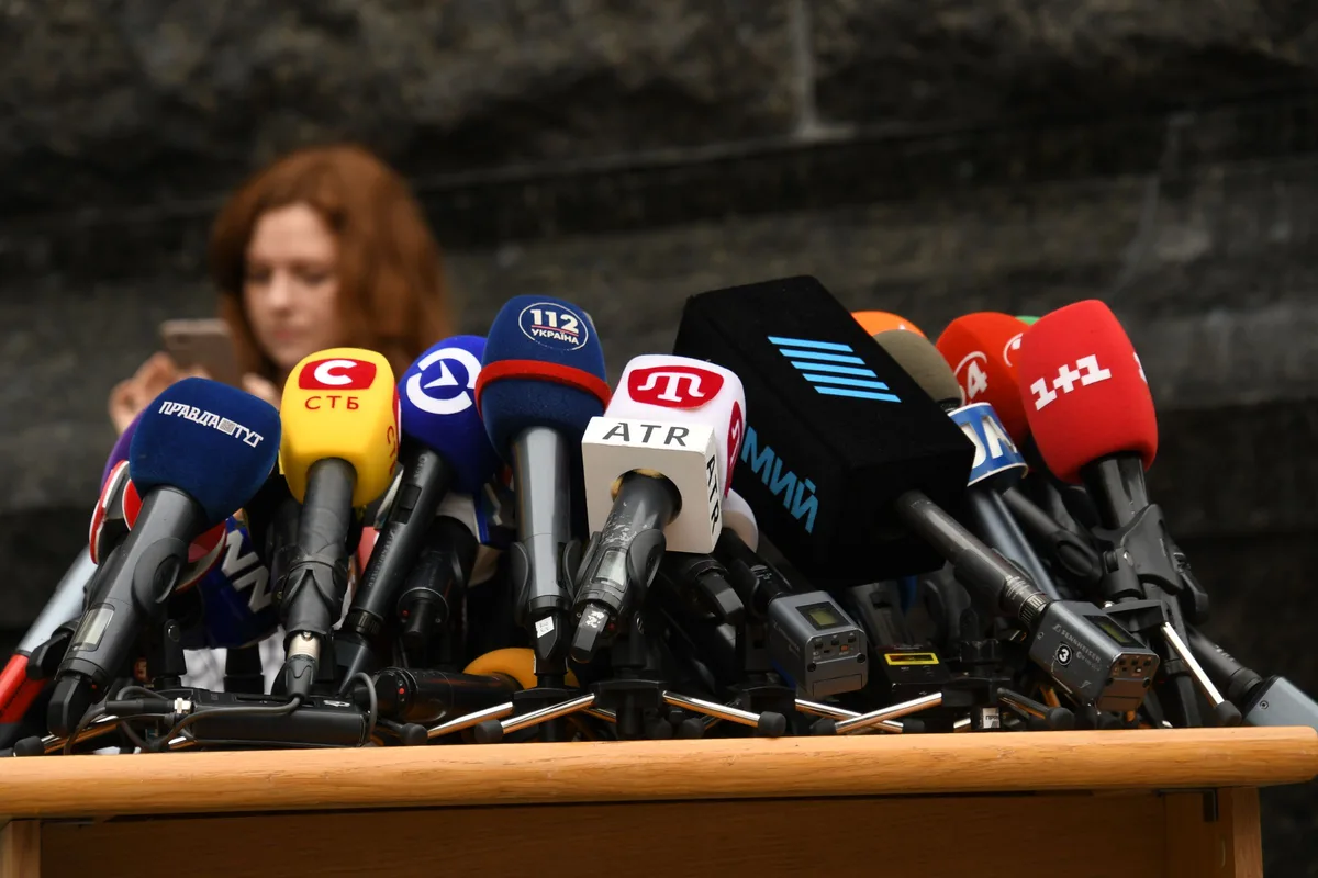 A bank of press microphones at a podium — the public apology, delivered to a wall of cameras, is the second act in Korea's celebrity-comeback script