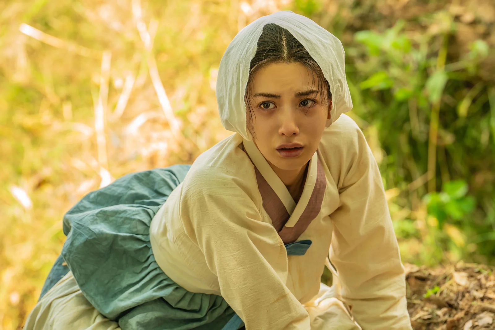 나나 as 희연, in a white headscarf and pale jeogori, crouched outdoors and looking up